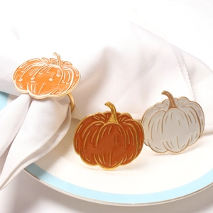 Detail of three pumpkin napkin rings in orange and cream enamel with gold metal finish