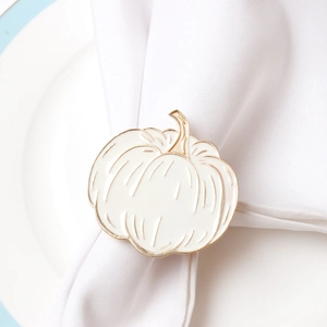 Detailed view of pumpkin napkin ring with white enamel finish and gold edges on white linen