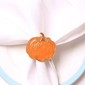 Macro shot of orange enamel pumpkin napkin ring with gold edges on white linen