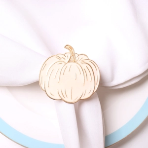 Close-up of cream and gold pumpkin napkin ring on a white fabric napkin and ceramic plate