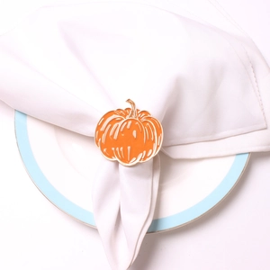 Detail of orange pumpkin napkin ring with gold edges on white linen napkin