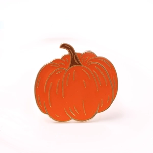 Detail shot of a pumpkin napkin ring with orange enamel and gold-plated metal finish