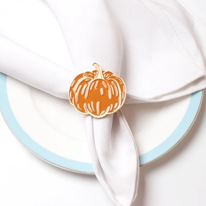 Detailed view of an orange pumpkin napkin ring with gold edges on a white cloth napkin