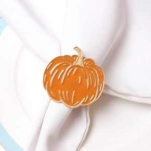Detailed macro view of an orange pumpkin napkin ring with gold trim on a white plate