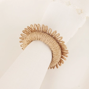 Handcrafted raffia napkin ring with wavy edges on white linen cloth for table decor