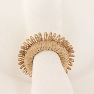Handmade raffia napkin ring with natural woven texture on a white cloth napkin