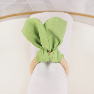 Easter rabbit ear napkin ring with light wood circle and green fabric tie on white plate