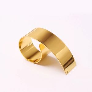 Polished gold metal ribbon napkin ring with elegant curved design and mirror finish