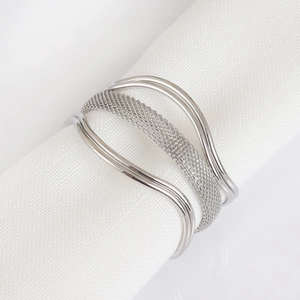 Close-up of silver metal woven napkin ring with multi-layer wave design on white napkin