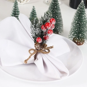 Detail of Christmas napkin ring with red berries, pine needles and a rustic burlap bow