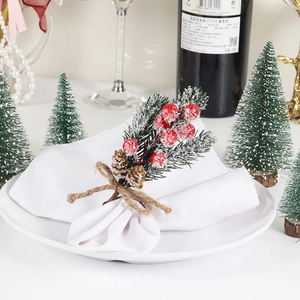 Christmas napkin ring with pine needles and red berries on a white plate set
