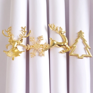 Detail of Christmas napkin rings set featuring golden deer, snowflake, and tree designs