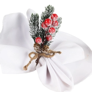 Christmas cedar and red berry napkin ring with pine cones on a white ceramic plate