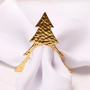 Hammered golden Christmas tree napkin ring on a white cloth for festive table setting