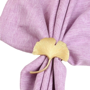 Matte gold ginkgo leaf napkin ring with detailed texture on a purple fabric napkin
