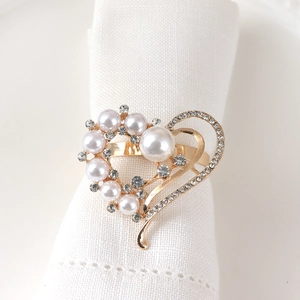 Golden heart napkin ring with pearls and rhinestones on a white linen napkin