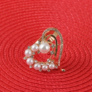 Elegant gold heart napkin ring with pearls and rhinestones on a red textured mat