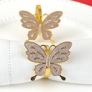 Elegant gold butterfly napkin ring with pink enamel and crystals on white cloth