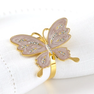 Golden butterfly napkin ring with pink enamel wings and rhinestones on white cloth