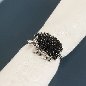 Rond de serviette hérisson vintage en argent sur serviette blanche et fond bleu