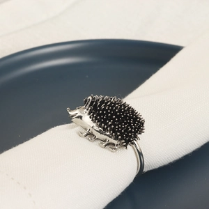 Détail du rond de serviette hérisson argenté avec texture précise sur lin blanc