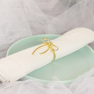 Elegant gold bow-shaped metal napkin ring on a white napkin and light green plate