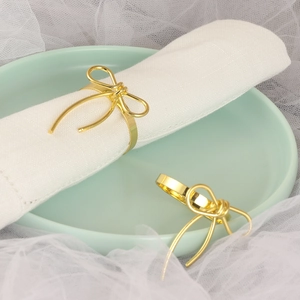 Elegant gold bow napkin rings set of two on white cloth for dining table decoration