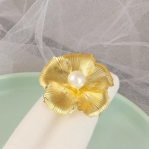 Rond de serviette fleur dorée avec perle sur nappe blanche et assiette vert clair