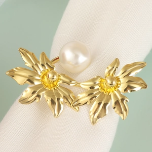 Elegant gold leaf and pearl napkin ring on a white cloth for luxury table decoration