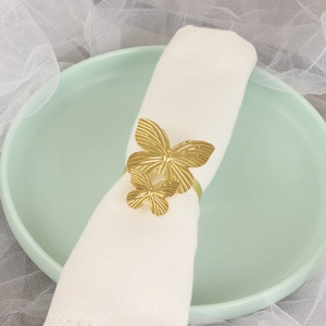Detail eines eleganten goldener Schmetterling Serviettenrings auf grünem Keramikteller