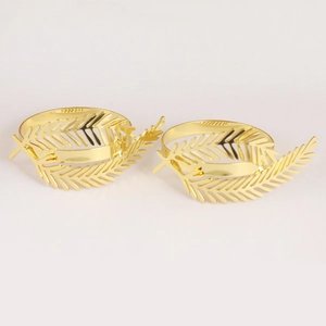 Set of two gold leaf cutout napkin rings with polished metallic finish on white background