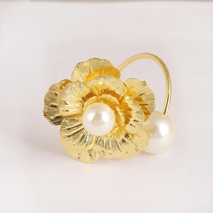 Détail macro du rond de serviette doré à fleurs avec perles et pétales ciselés