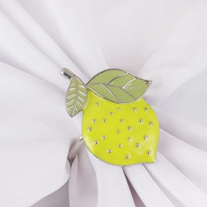 Bright yellow lemon napkin ring with green leaves on white fabric background