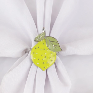 Yellow lemon napkin ring with green leaves on white linen for elegant table setting