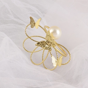 Elegante servilletero de mariposa dorada con perla blanca sobre suave velo blanco