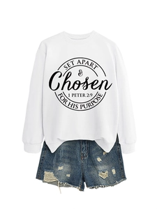 Close-up of white crewneck sweatshirt with biblical text art and ripped denim shorts