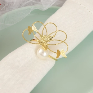 Elegante servilletero de mariposa dorada con perla sobre una servilleta de tela blanca