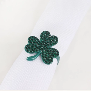 Green rhinestone four-leaf clover napkin ring holder on white linen for dining table décor