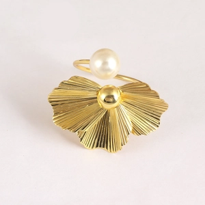 Bague ouverte feuille de ginkgo dorée avec perle sur un fond gris épuré