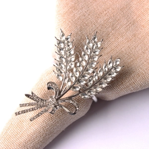 Close-up of silver napkin ring with crystal-encrusted wheat ear and ribbon bow design