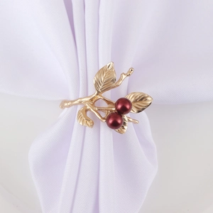 Golden twig napkin ring with red berry details on white linen fabric for table setting