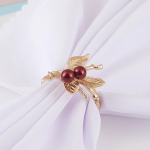 Detailed macro shot of golden leaf and red berry napkin ring on white fabric