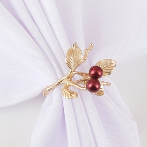 Golden branch napkin ring with red berry details on a white fabric napkin for table decor