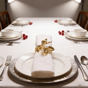 Close-up of golden leaf napkin ring with white pearls on elegant festive dinner table