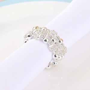 Three-row rhinestone beaded napkin ring with silver metal spacers on a white dinner plate