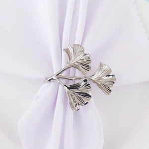 Rond de serviette élégant en argent avec feuilles de ginkgo sur une serviette blanche