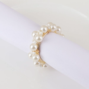 Elegant gold metal woven napkin ring featuring layered cream white pearls on white cloth