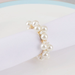 Detail of cream white pearls and gold wire woven napkin ring on a white napkin
