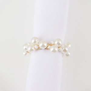 Close-up of elegant woven pearl napkin ring with gold wire detail on white napkin