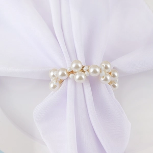 Elegant white pearl and gold wire woven napkin ring on a white fabric napkin decoration
